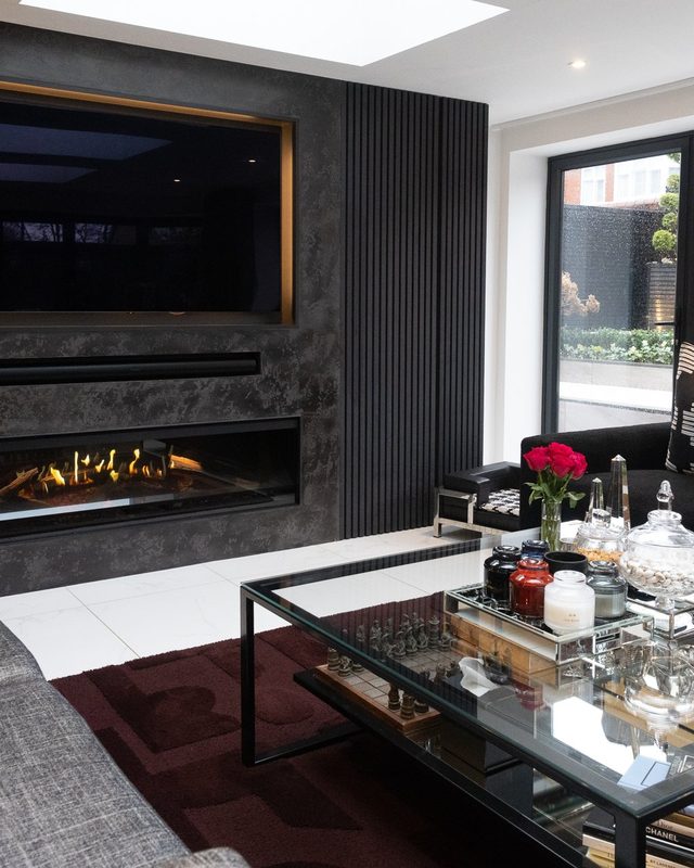 Sycamore living room with a long fire, dark panelling and a glass coffee table